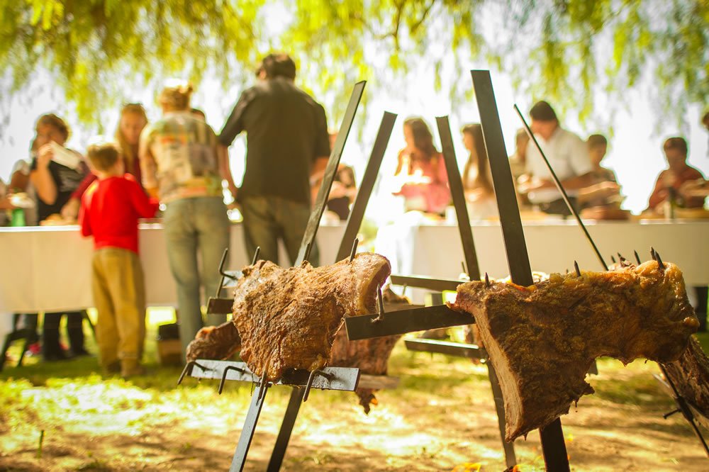 Comida sanjuanina al aire libre con mesas familiares al fondo
